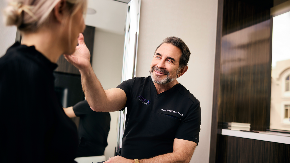 Dr Paul Nassif assessing a patient's face during a consultation