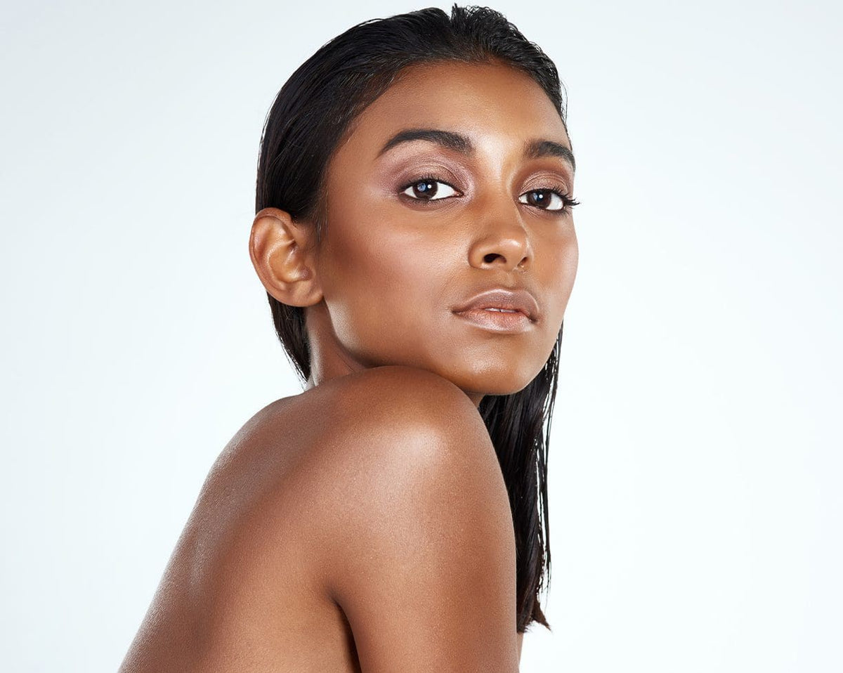 Woman with glowing skin looking over her shoulder