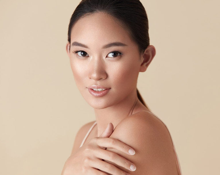 Woman with smooth skin resting a hand on her shoulder